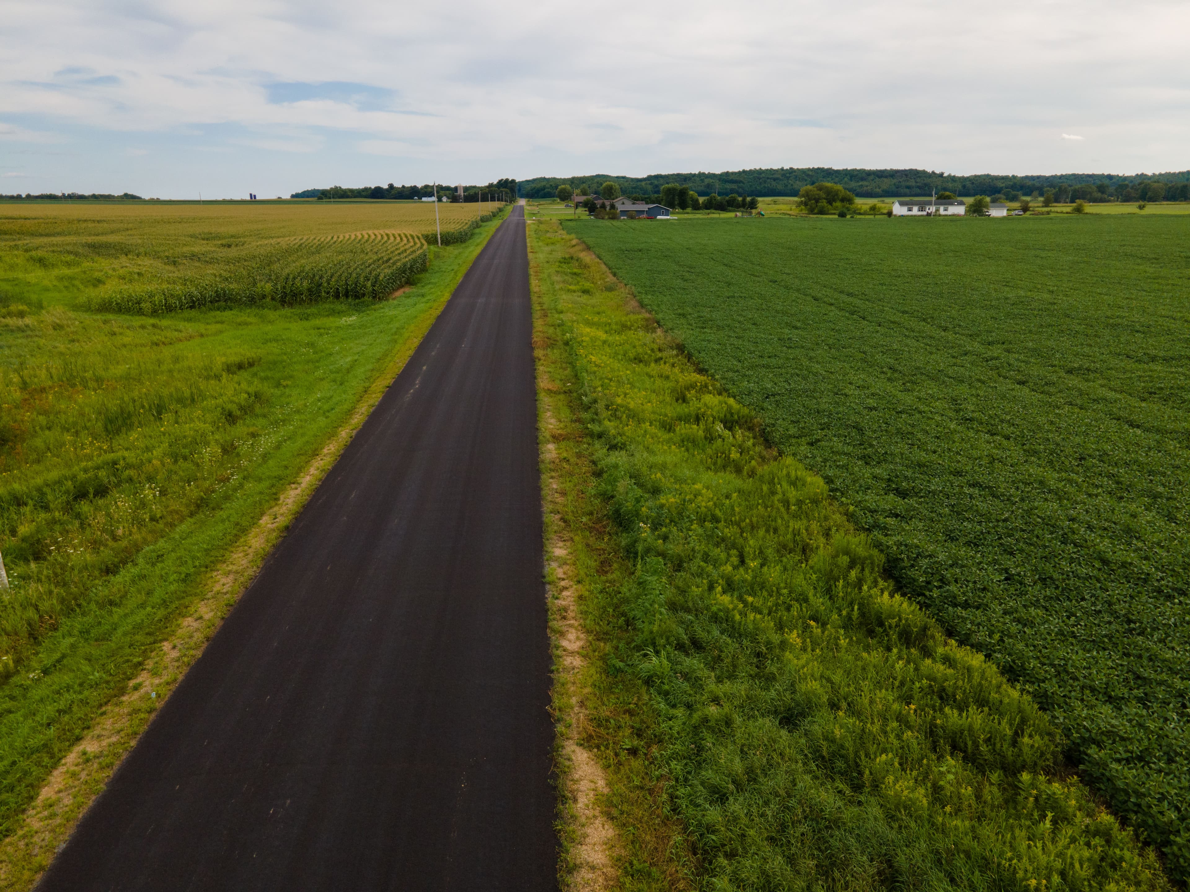 Aerial photograph of a road cutting between green rural fields.