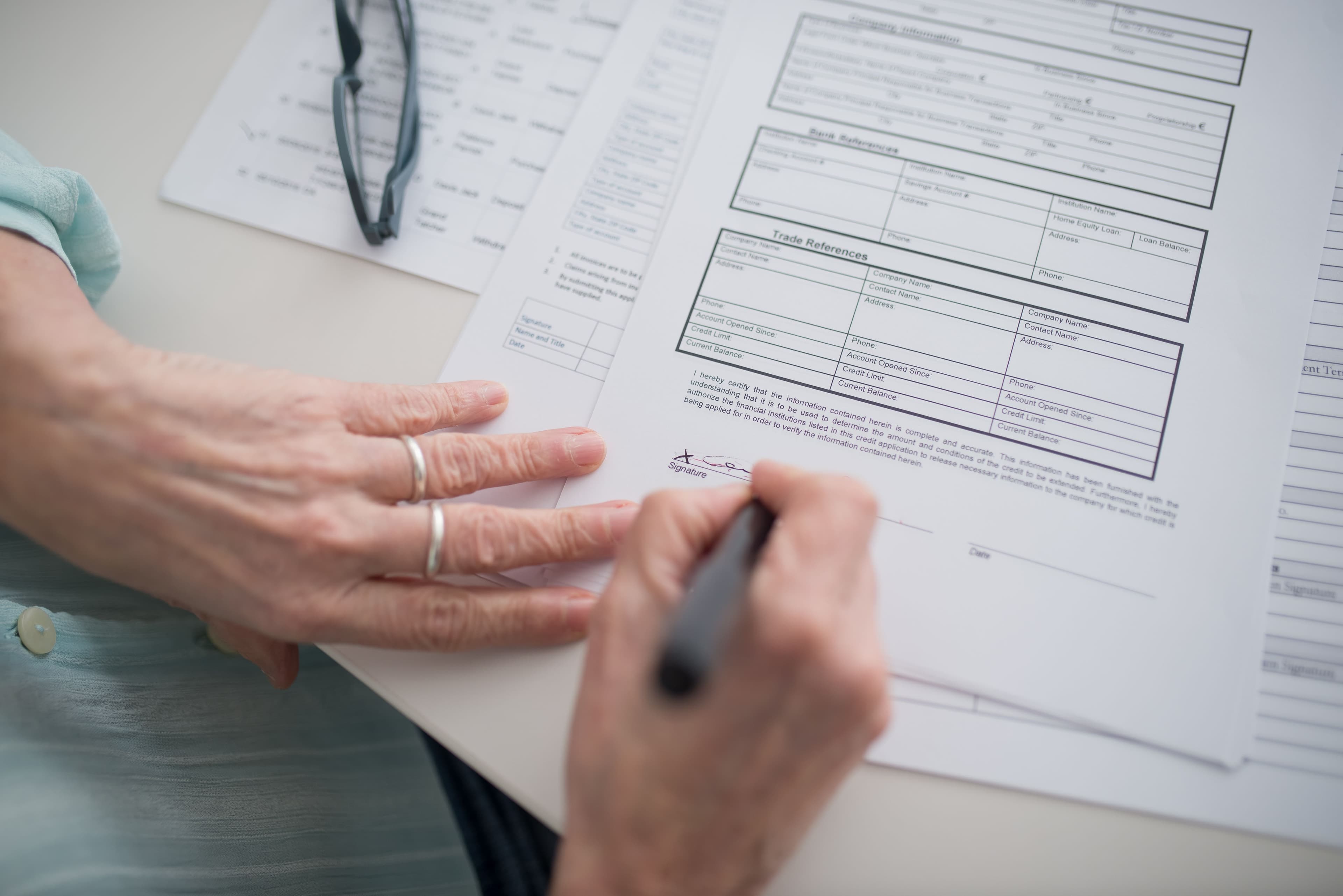 A hand signing a document with a pen