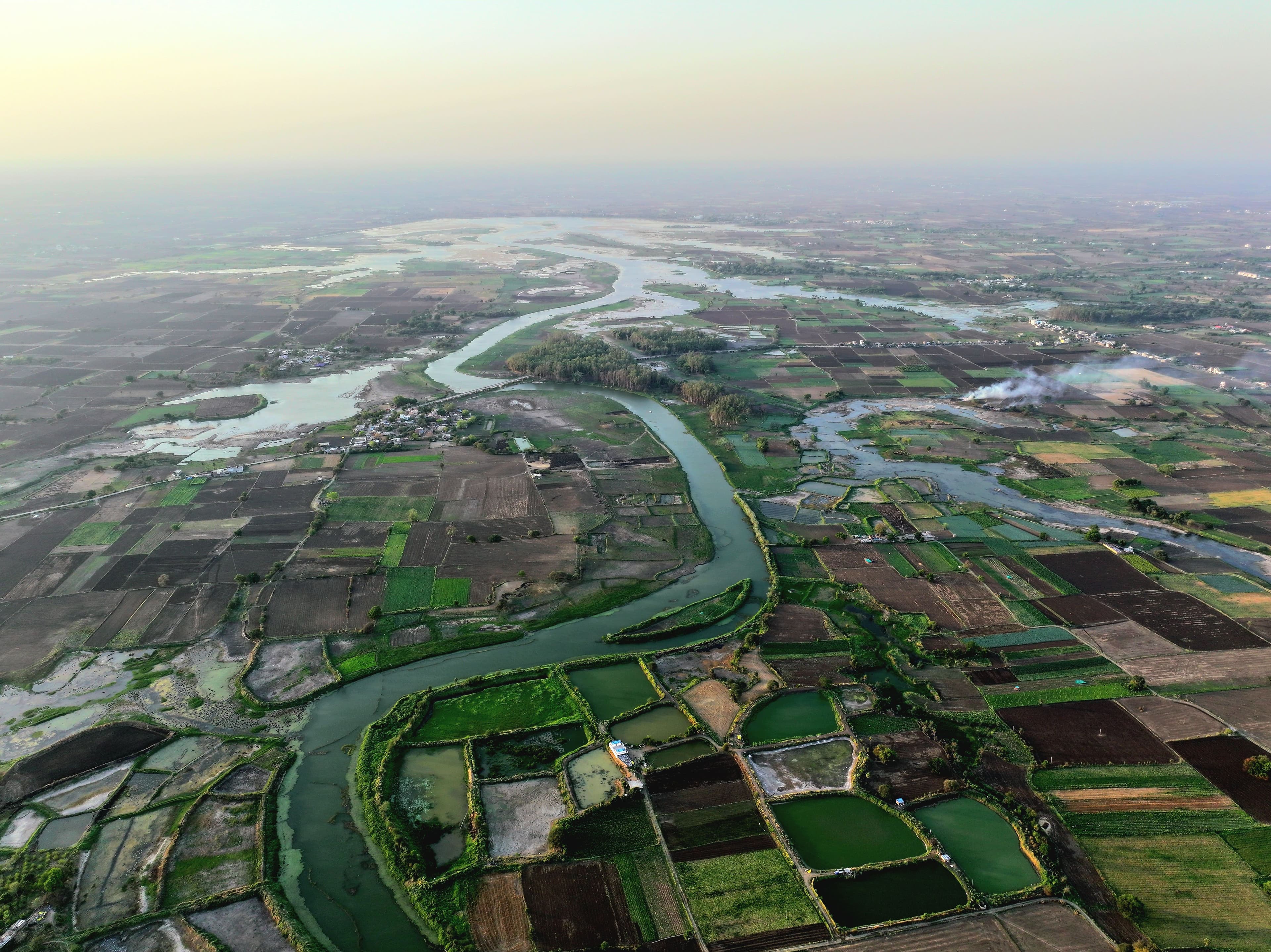 Aerial photograph of fields and a winding river in a broad rural landscape.